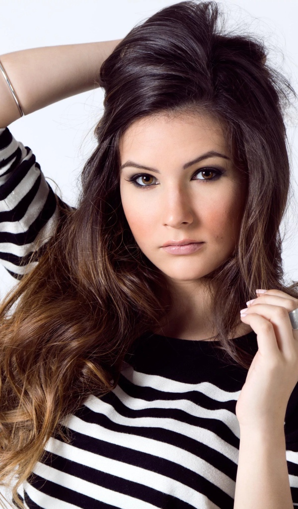 Девушка в полосатом свитере с рукой в волосах на белом фоне