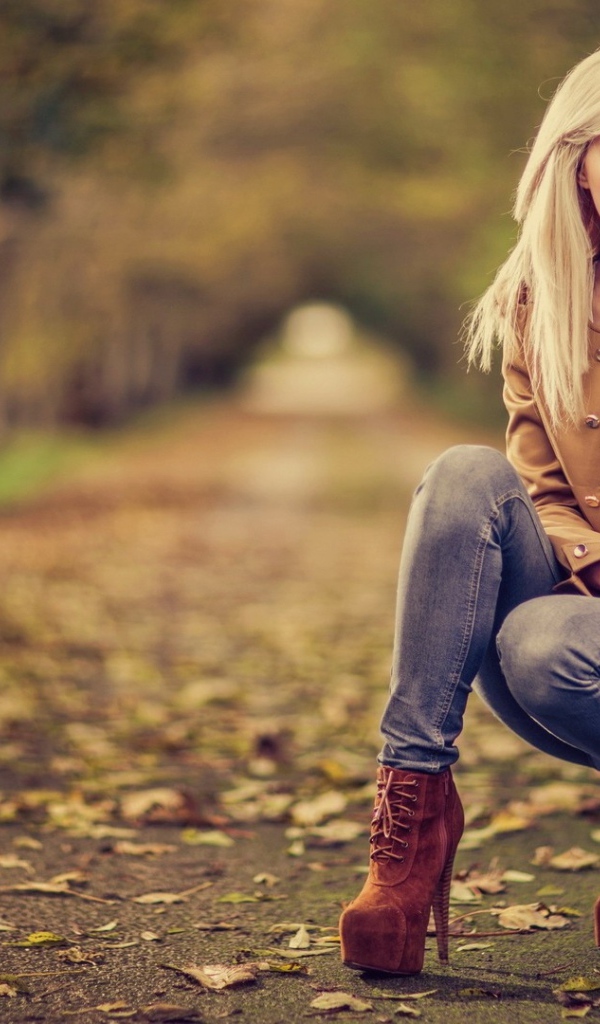 Девушка на высоких каблуках сидит на корточках в парке