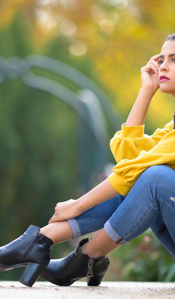 Девушка в джинсах сидит на земле 