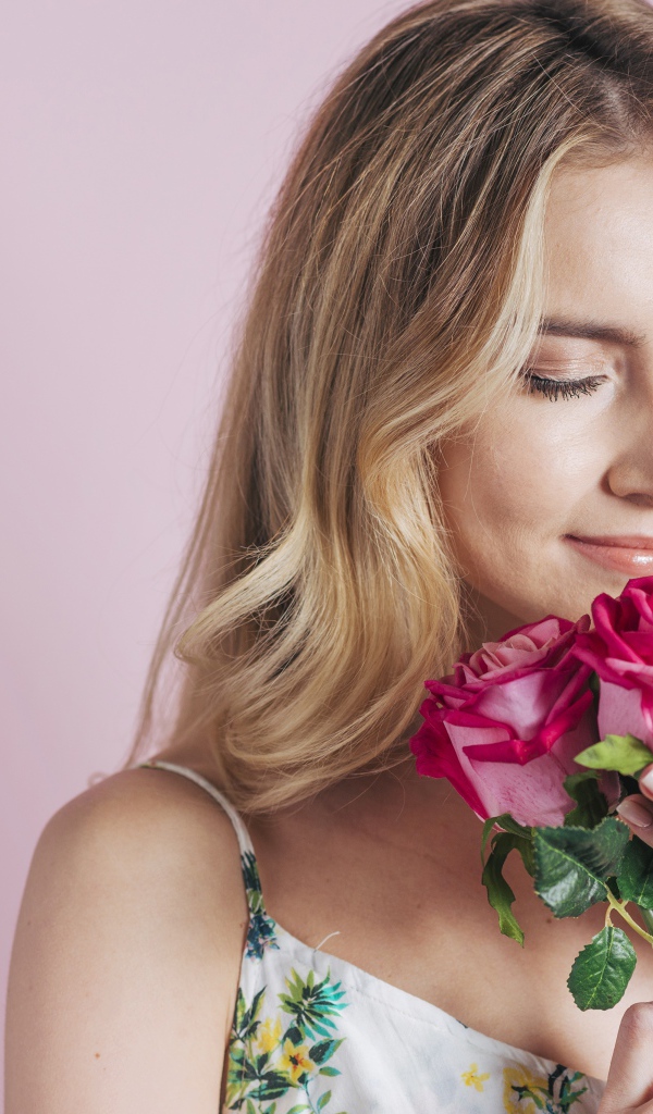 Девушка вдыхает аромат роз  