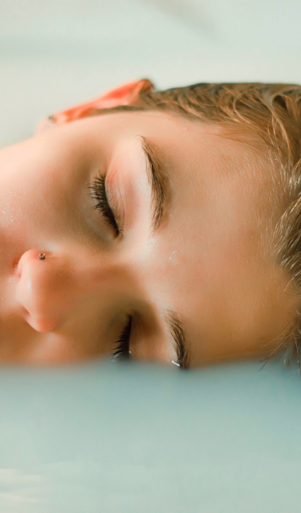 Девушка лежит с закрытыми глазами в ванной
