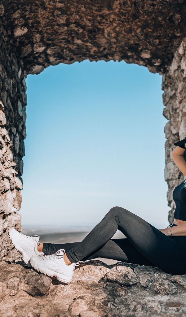 Девушка сидит в окне старого здания 