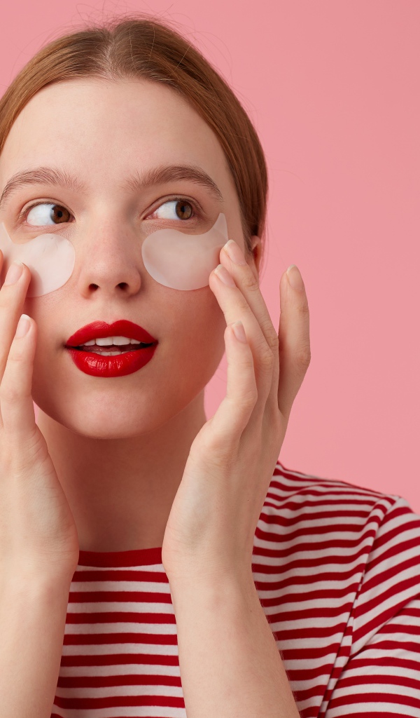 Девушка приклеивает патчи для глаз на лицо 