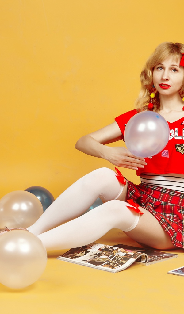 Девушка с шариками и журналами сидит на полу