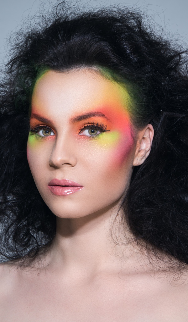 Девушка с начесом на волосах с ярким макияжем на сером фоне