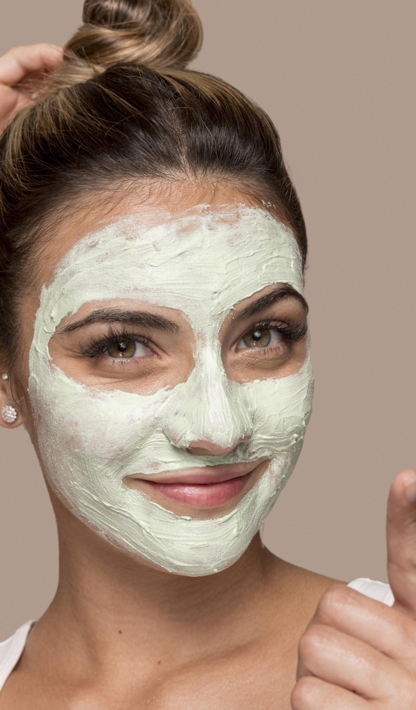 Девушка с завязанными волосами с косметической маской на лице