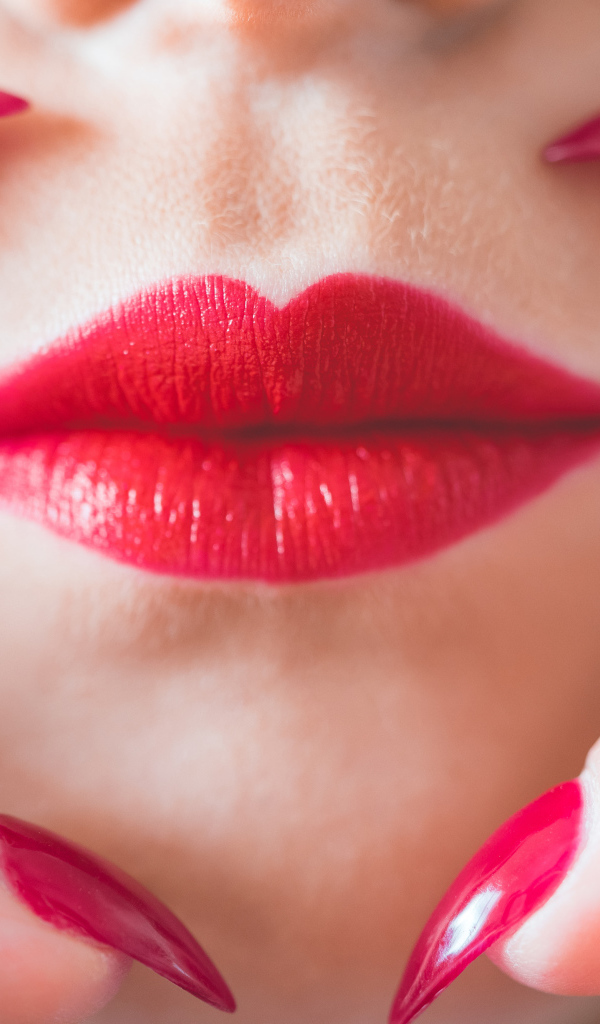 Руки с длинными красными ногтями у губ
