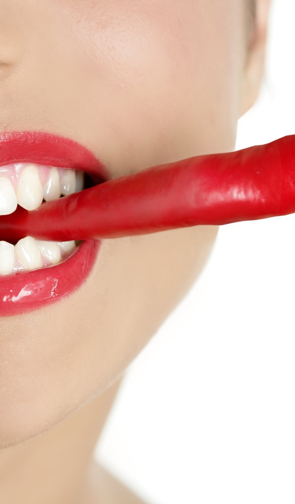 Hot pepper in a girl’s mouth with beautiful white teeth