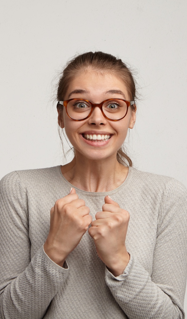 Радостная девушка в очках для зрения на сером фоне 