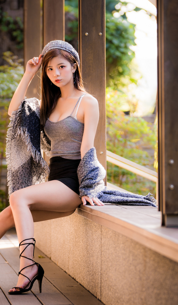Длинноногая азиатка сидит на окне 