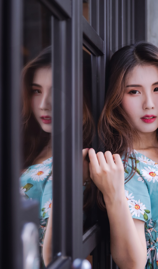 Длинноволосая девушка азиатка стоит у окна