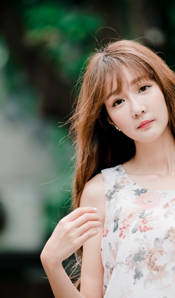 Длинноволосая азиатка стоит у стены 