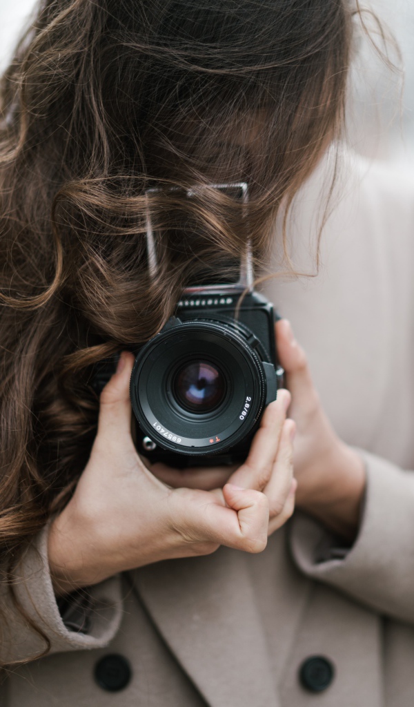 Длинноволосая девушка с фотоаппаратом в руках 