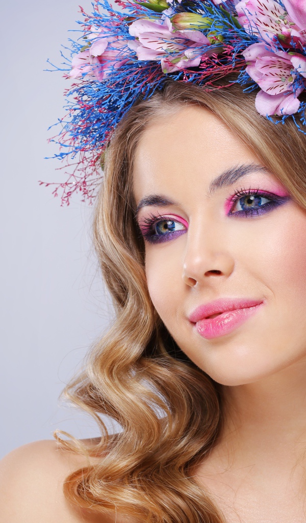 Милая девушка с венком на голове на сером фоне 