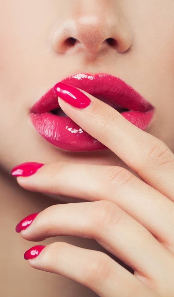 Розовые губы и розовый маникюр девушки крупным планом