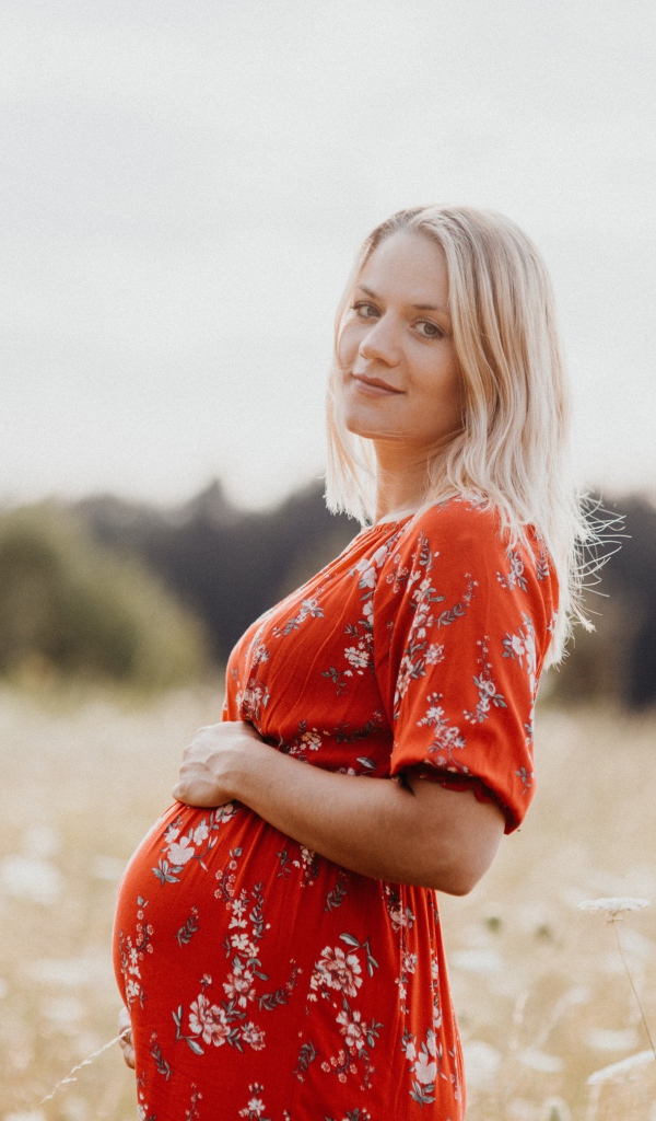 Беременная девушка в красном платье на поле