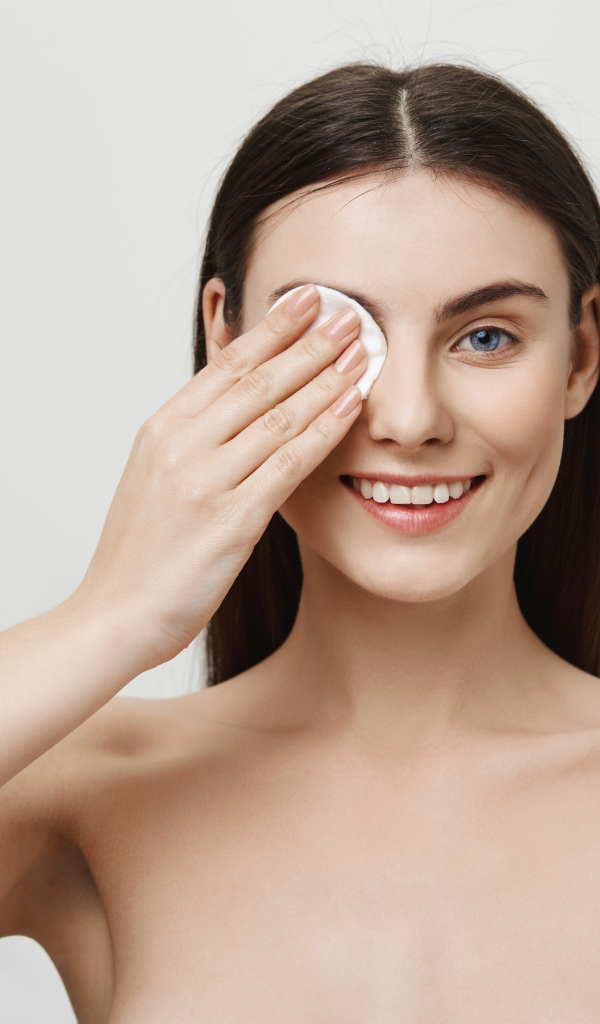 Настоящая голубоглазая девушка снимает макияж с лица