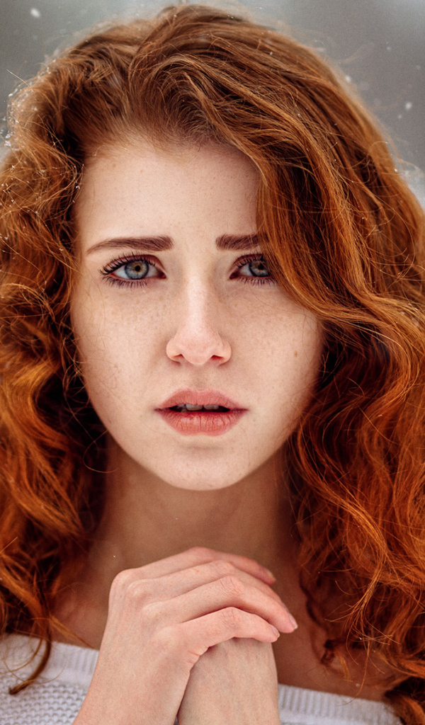 Рыжеволосая девушка замерзает на улице зимой