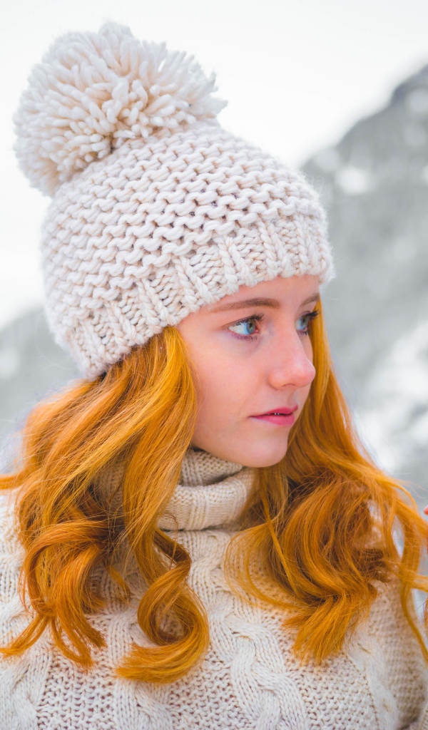 Рыжеволосая девушка в теплой шапке зимой 