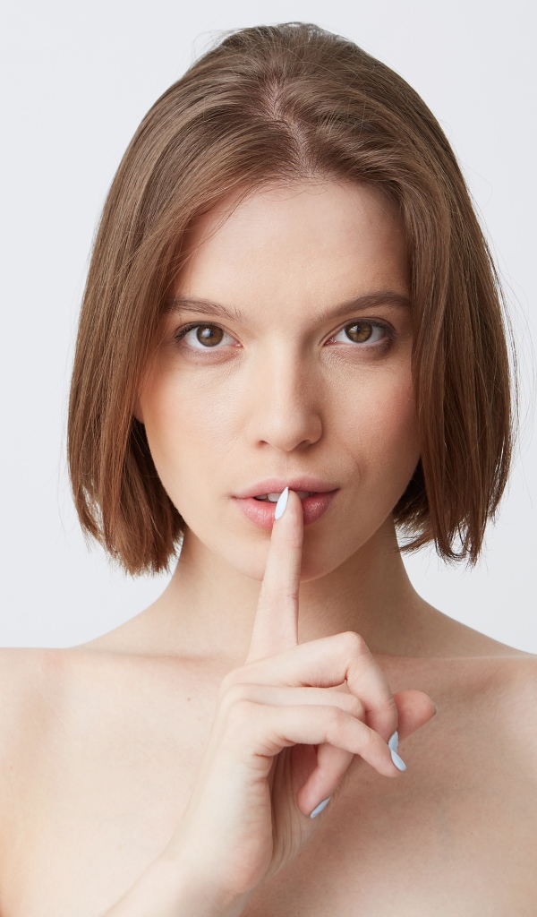 Девушка с короткой стрижкой с пальцем у рта 