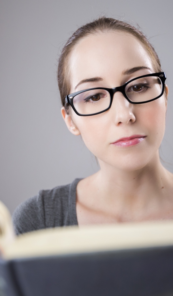 Умная девушка в очках читает книгу 