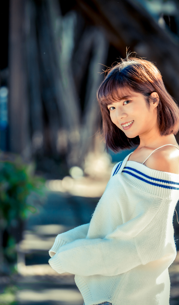 Улыбающаяся девушка азиатка в белом свитере 