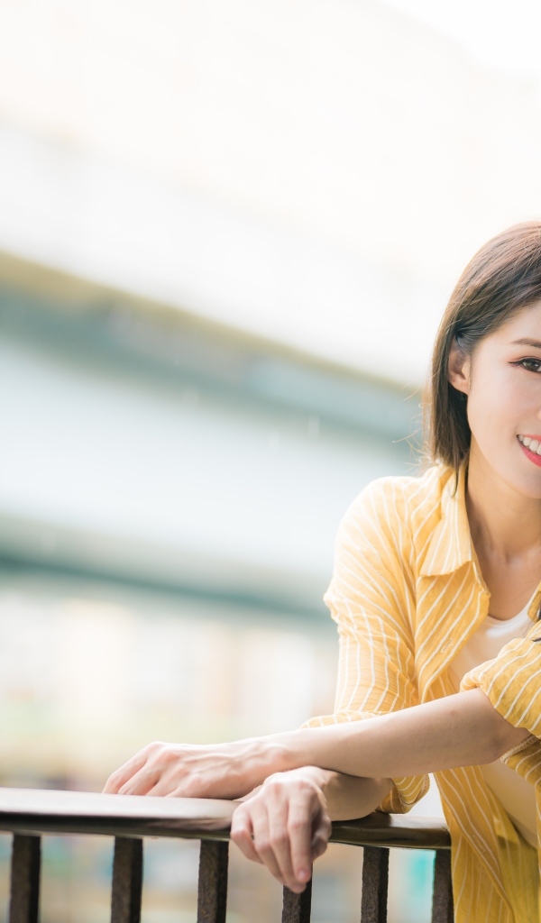 Улыбающаяся азиатка в желтой полосатой рубашке