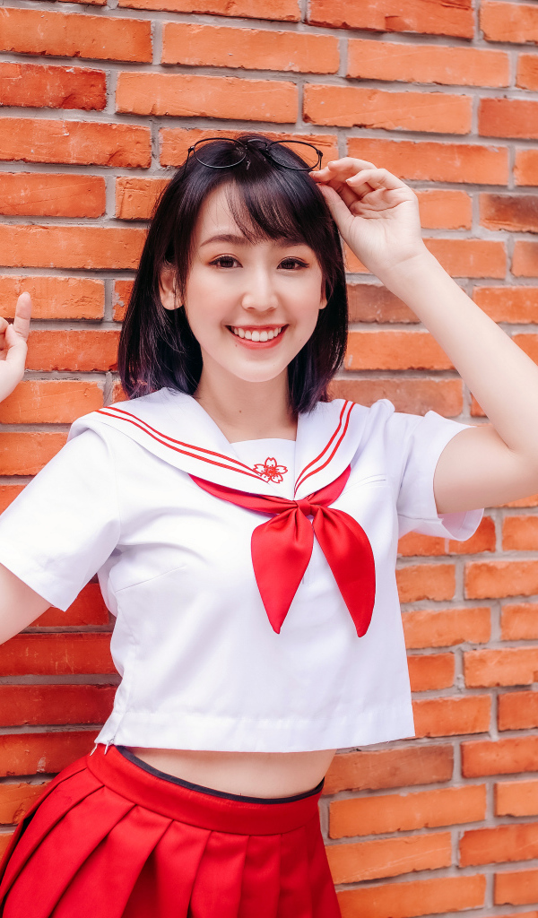 Улыбающаяся азиатка стоит у стены 