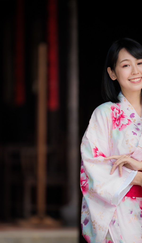 Улыбающаяся девушка азиатка в кимоно с веером в руке