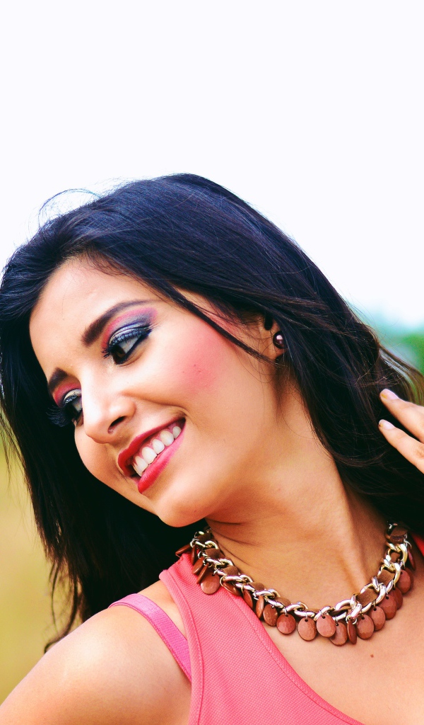 Улыбающаяся темноволосая девушка с украшением на шее 