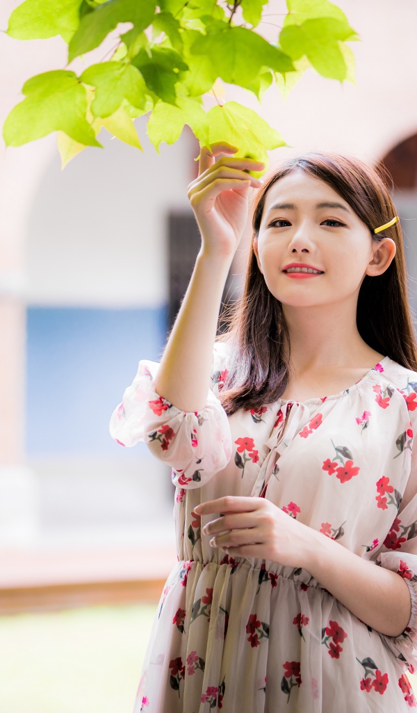 Улыбающаяся девушка в платье у дерева 