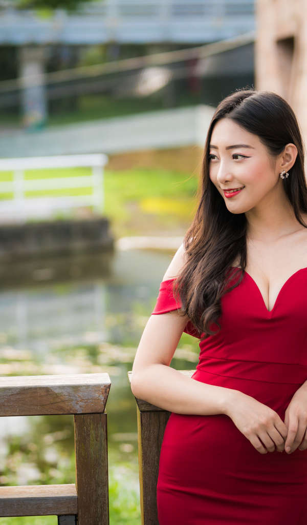 Улыбающаяся девушка в красном платье у перил 