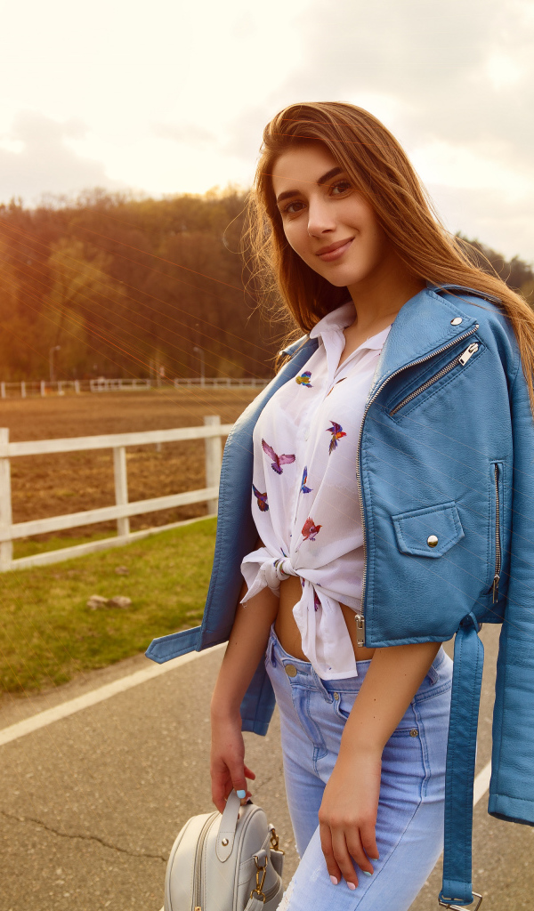 Улыбающаяся девушка в синей кожаной куртке на дороге 
