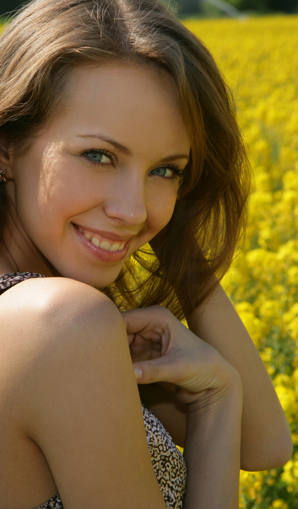 Улыбающаяся девушка на фоне поля с желтыми цветами