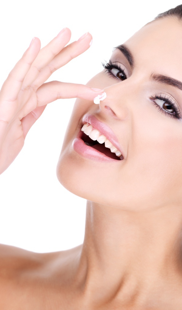 Улыбающаяся девушка мажет крем на нос 