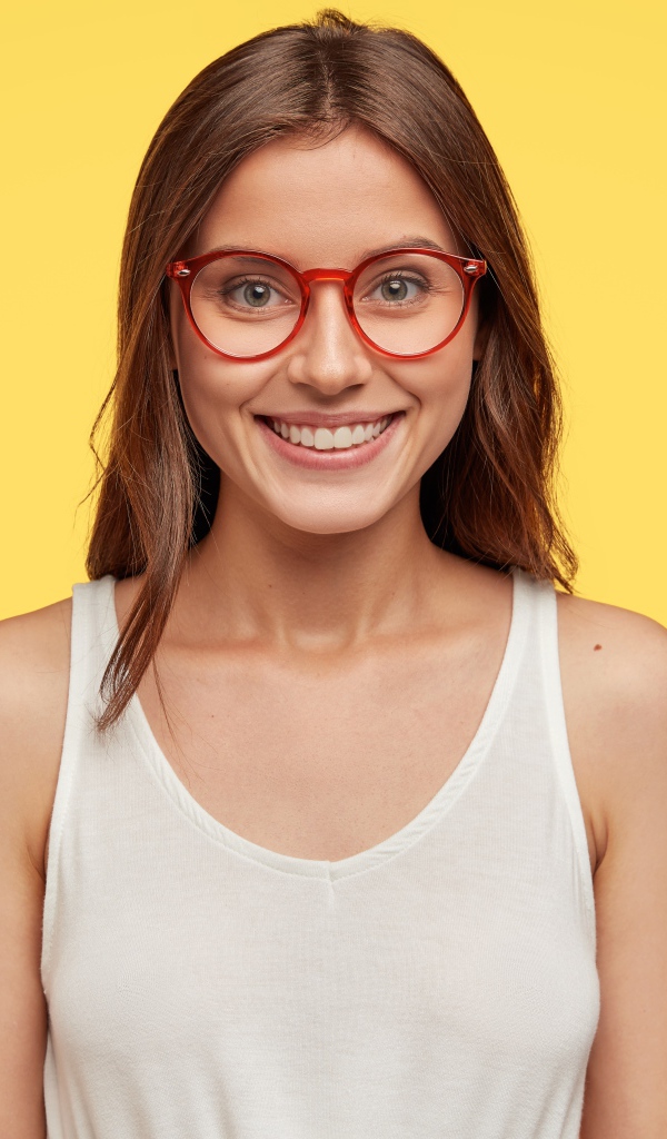 Улыбающаяся девушка в очках на желтом фоне 