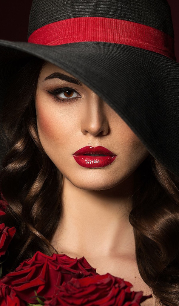 Эффектная девушка в большой черной шляпе с букетом роз