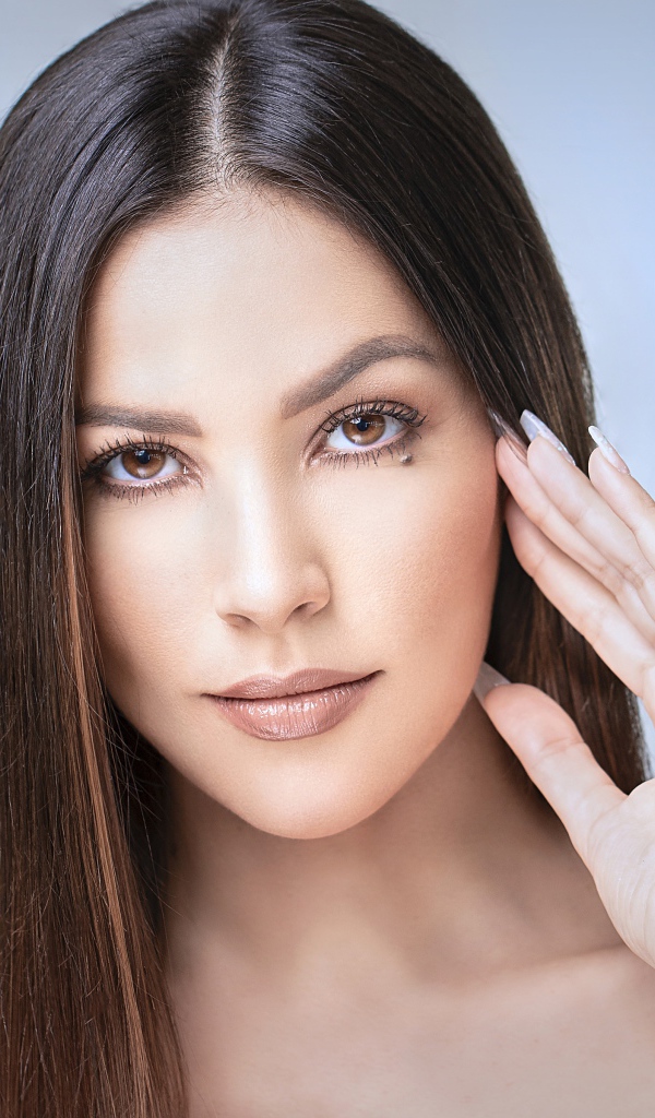 Стильная кареглазая длинноволосая брюнетка с рукой у лица