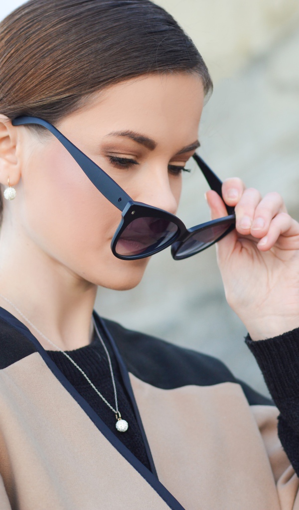 Стильная девушка с прической снимает очки