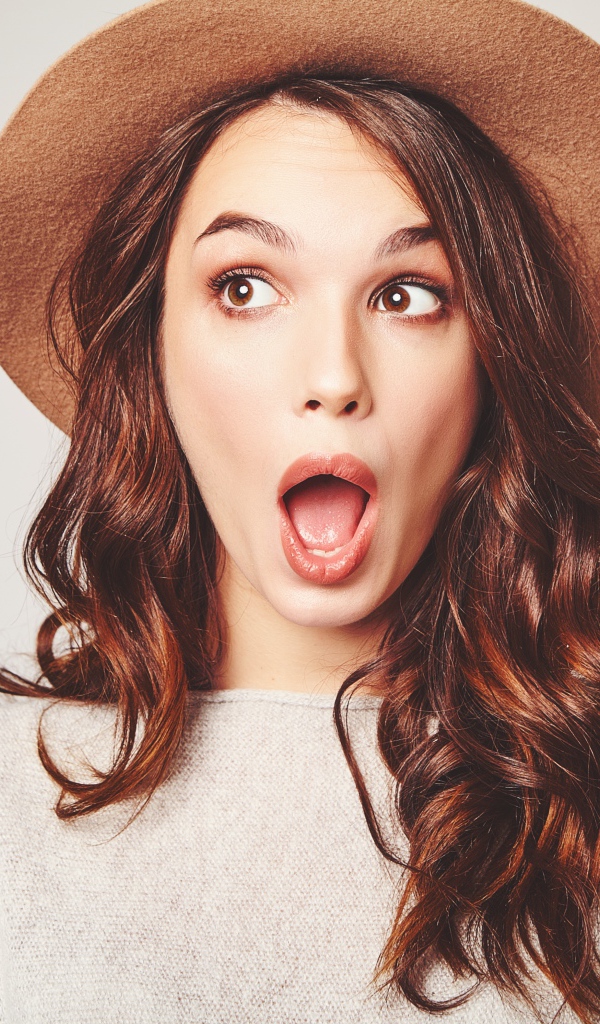 Удивленная девушка с длинными волосами в коричневой шляпе 