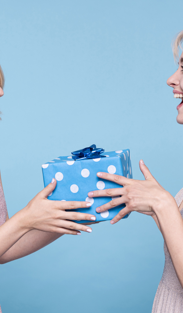 Две веселые подруги с подарком на голубом фоне