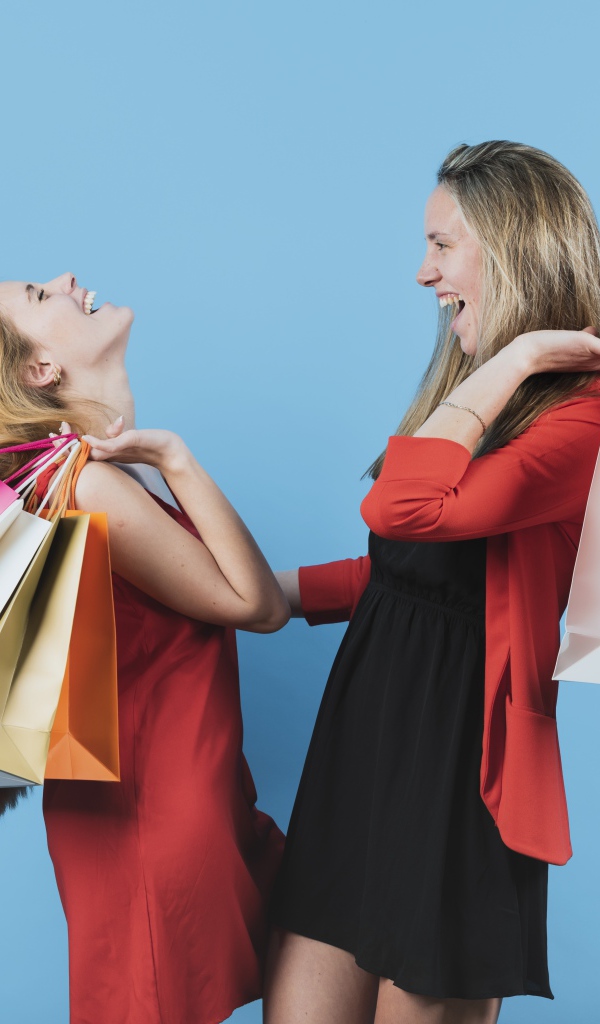 Две девушки с покупками на голубом фоне