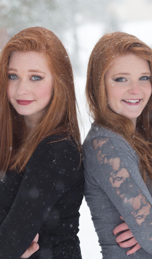 Две улыбающиеся рыжеволосые сестры на улице зимой 