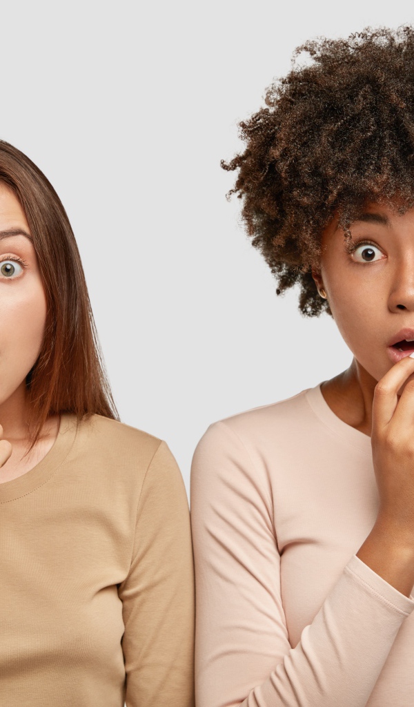 Две удивленные девушки на сером фоне 