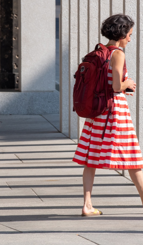 Женщина в красном полосатом платье с рюкзаком