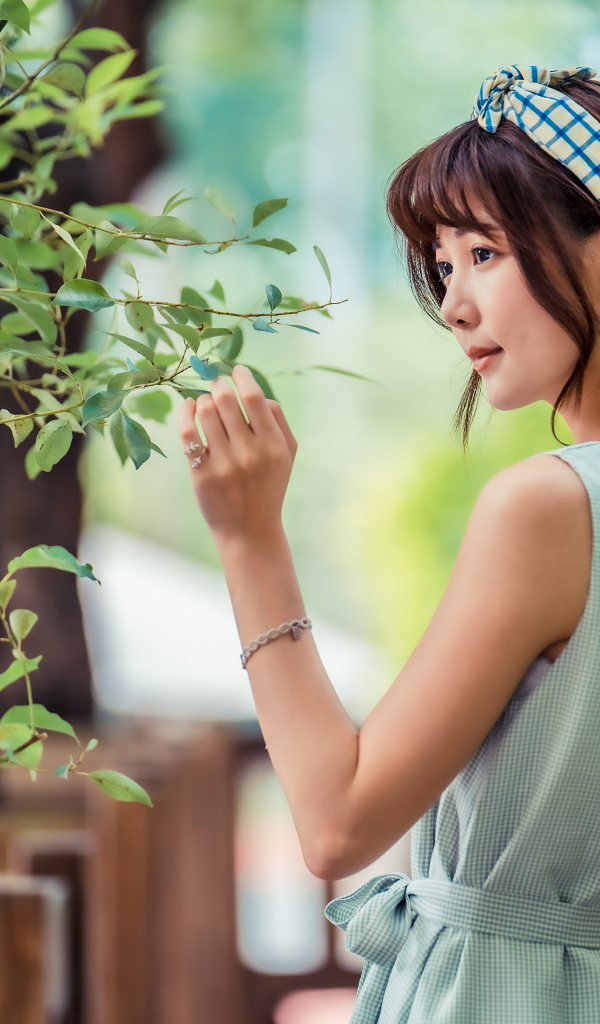 Молодая девушка азиатка с повязкой на голове у дерева 