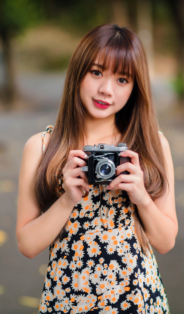 Молодая девушка азиатка с фотоаппаратом в руках 