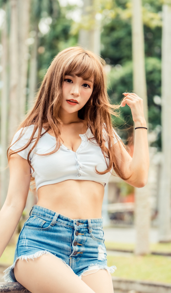 Молодая азиатка в коротком топе и синих шортах 