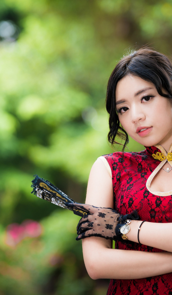 Молодая азиатка в красивом платье с веером в руке