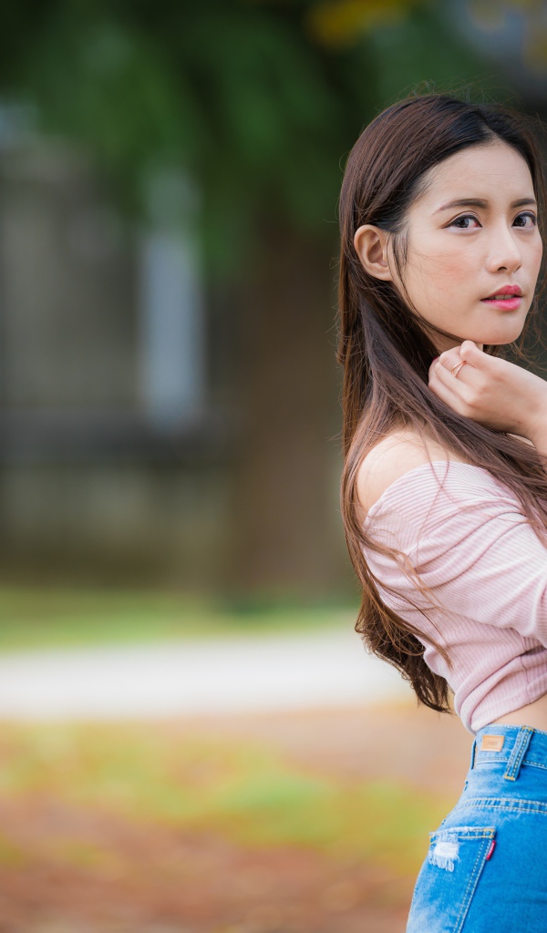 Молодая азиатка с длинными волосами в синих джинсах